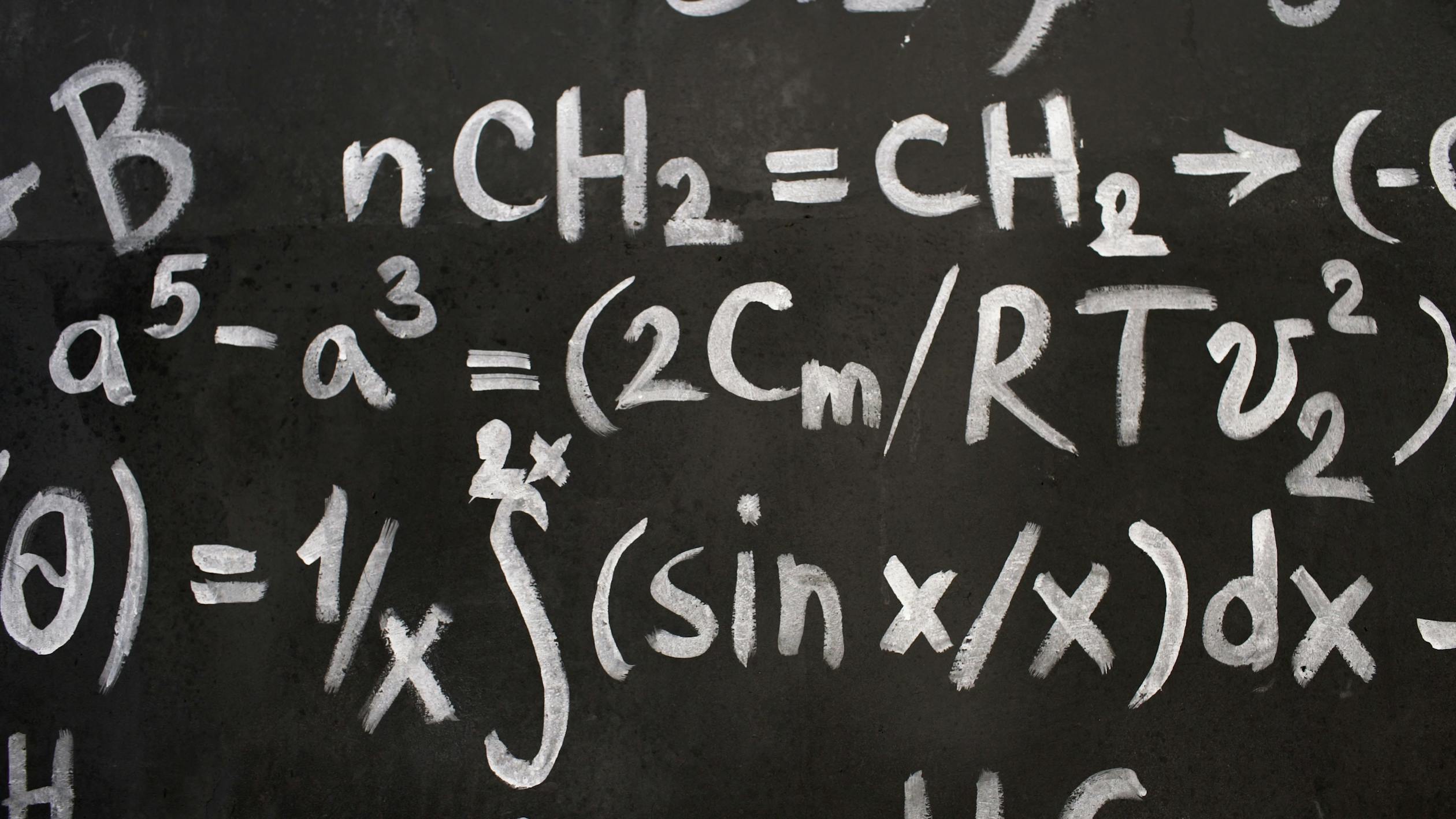 Close-up of complex equations on a chalkboard, showcasing chemistry and math symbols